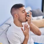 Un homme qui prend une bouffée d'air avec un appareil en se tenant la poitrine